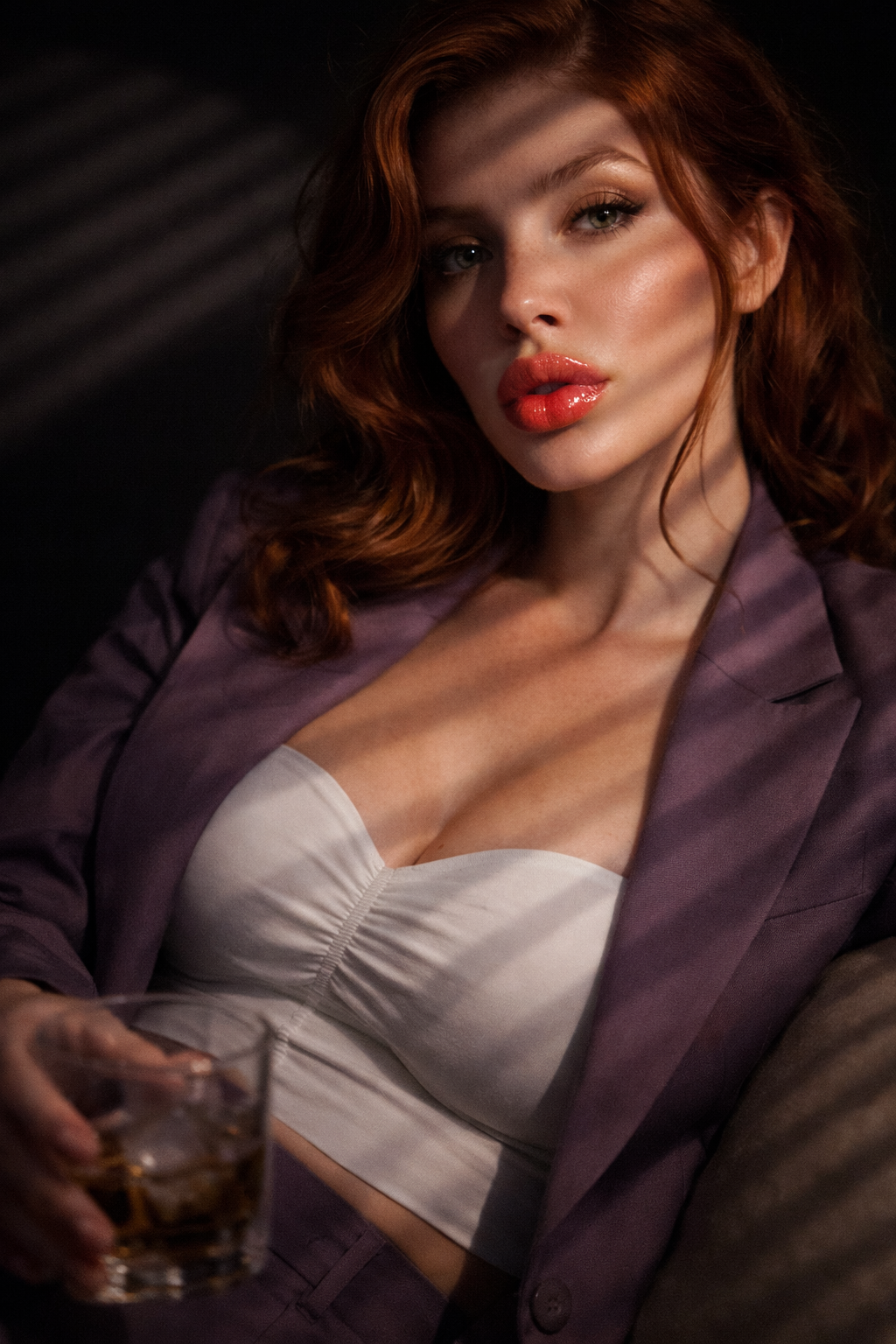 Woman holding a glass in a dimly lit setting. She is wearing Covets Yearn lip gloss.