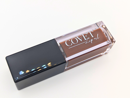 Angled view of Covet Lip Oil in Chocolate Cookie, a rich brown gloss with a soft sheen, photographed on a clean white background.