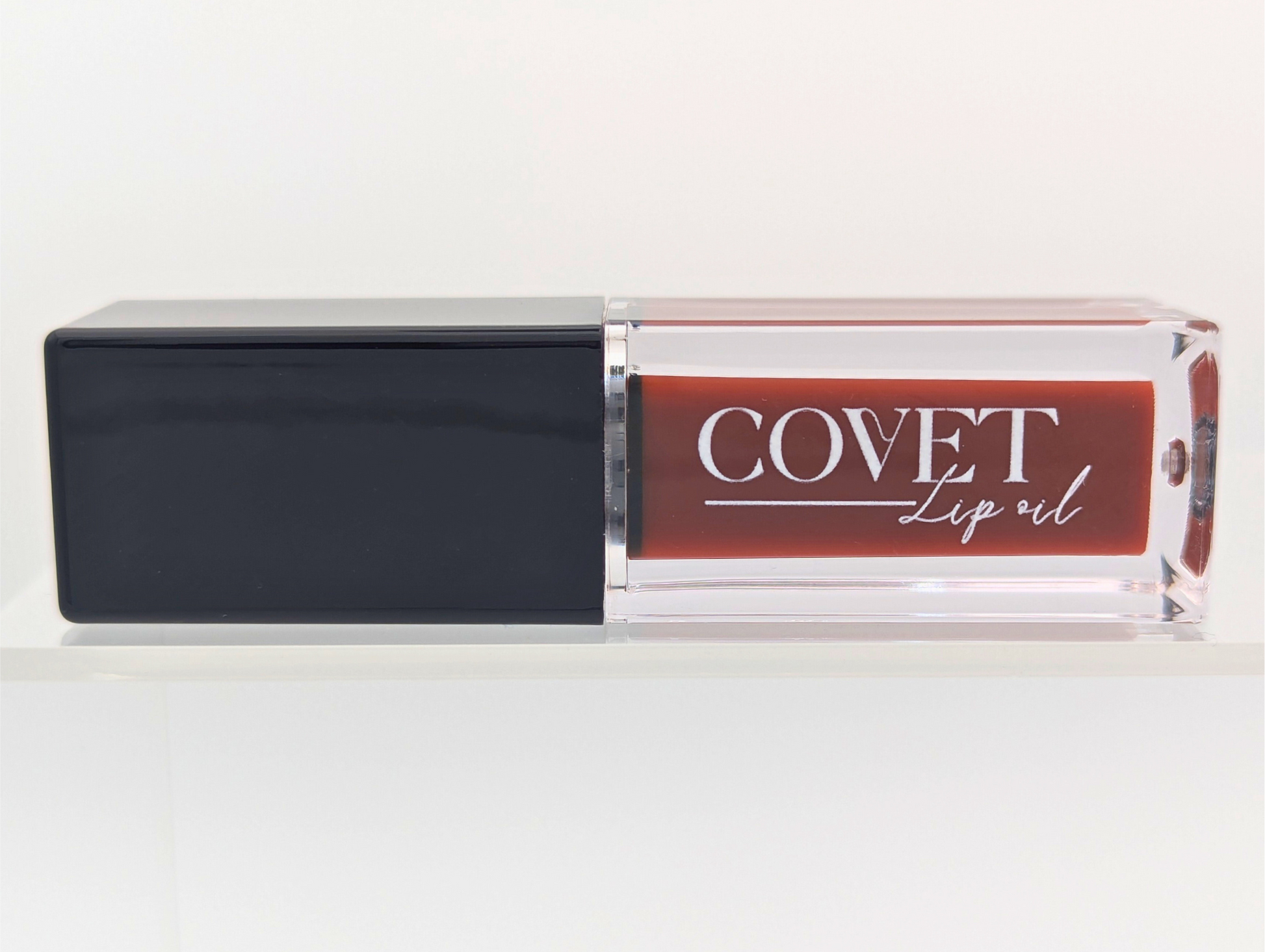 Front-facing Covet Hazelnut Cream lip gloss on a white background, highlighting the smooth hazelnut reddish brown tone.