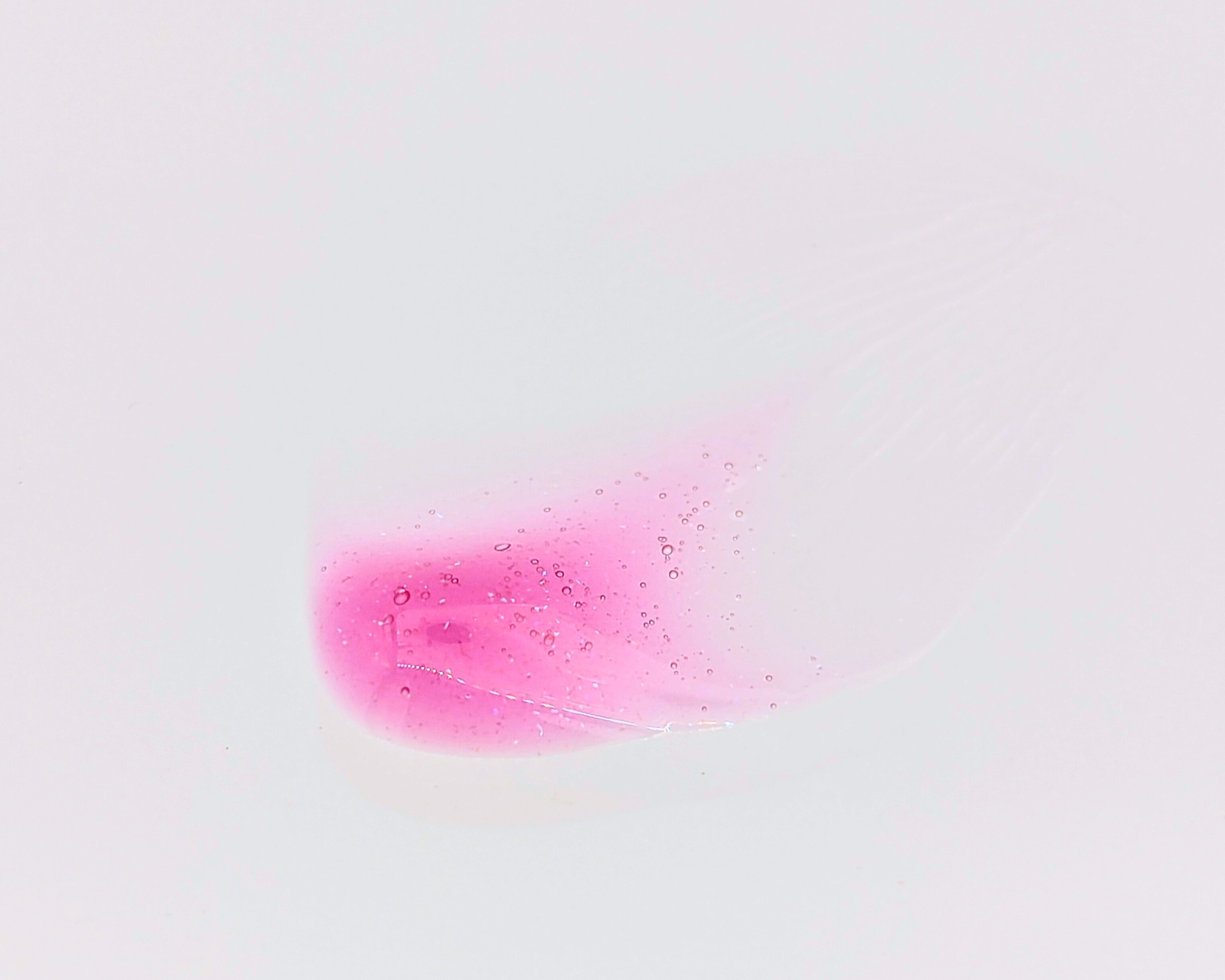 Swatch of Covet Beauty’s Maple Love lip gloss — a sheer raspberry pink gloss with fine shimmer on a white background.