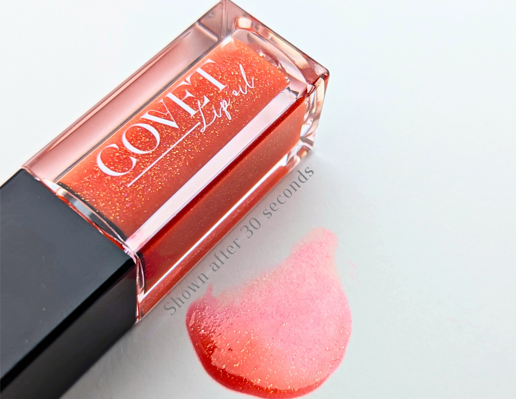ovet Beauty Mars lip gloss — warm coral-orange gloss with fine gold shimmer, shown in a clear square tube and swatched on a white background after 30 seconds of bloom.