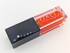 Covet Beauty’s Mars – Rust Bloom lip gloss stain— a vibrant orange gloss in a rectangular tube with black cap. Transforms into a soft coral pink based on skin pH and heat.