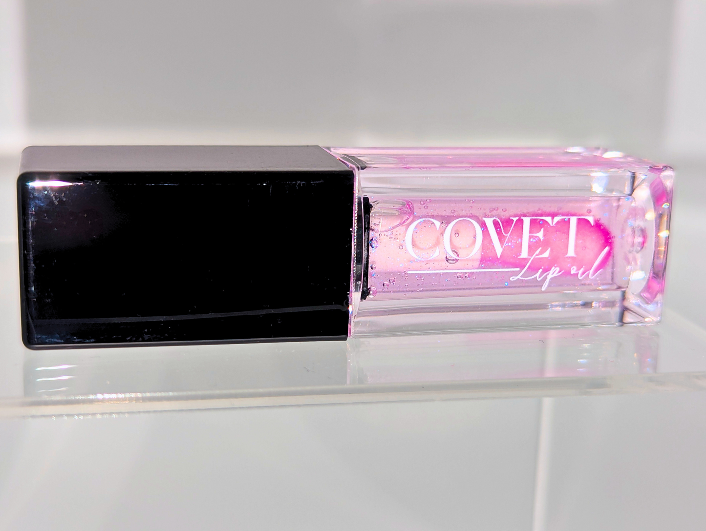 Covet Beauty’s Ocean of Stars lip gloss — a sheer violet gloss in a clear rectangular tube with black cap. Transforms into a soft cool pink based on skin pH and heat.