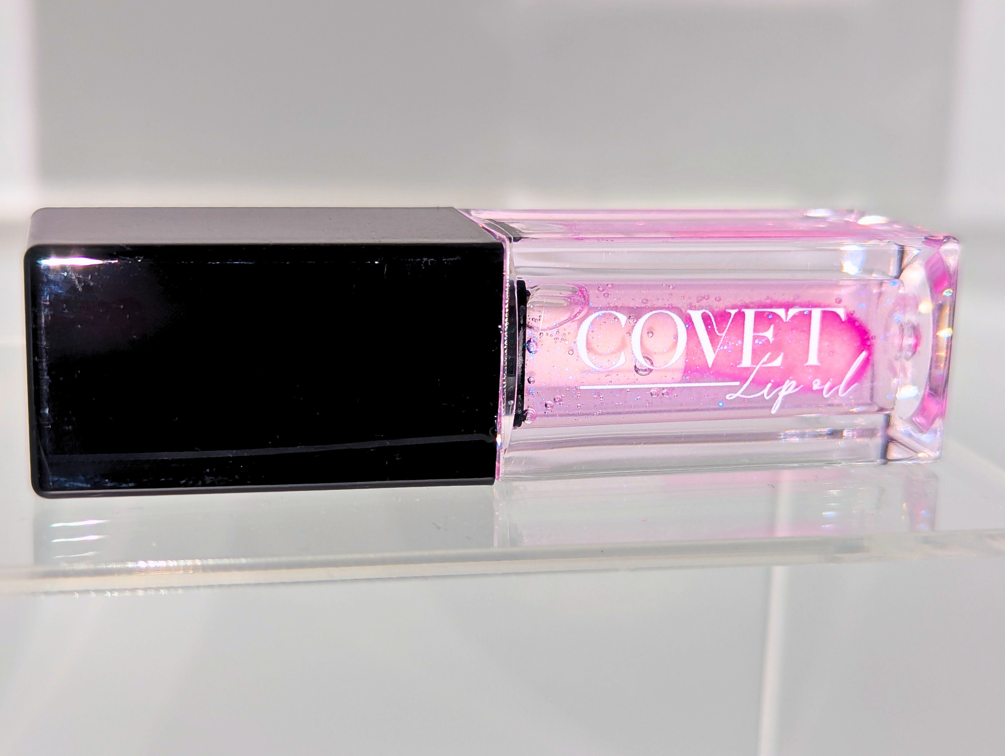 Covet Beauty’s Ocean of Stars lip gloss — a sheer violet gloss in a clear rectangular tube with black cap. Transforms into a soft cool pink based on skin pH and heat.