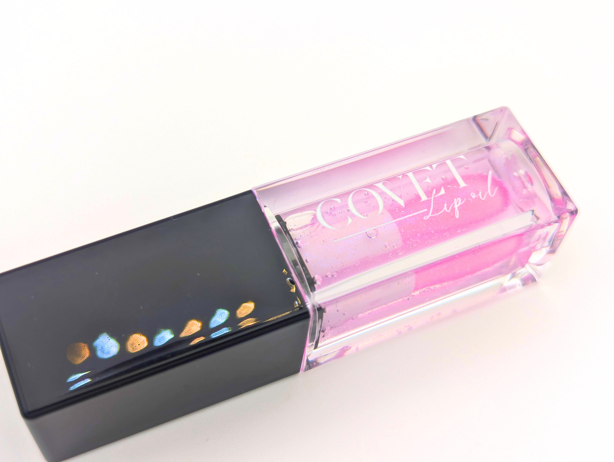 Covet Beauty’s Ocean of Stars lip gloss — a sheer violet gloss in a clear rectangular tube with black cap. Transforms into a soft cool pink based on skin pH and heat.