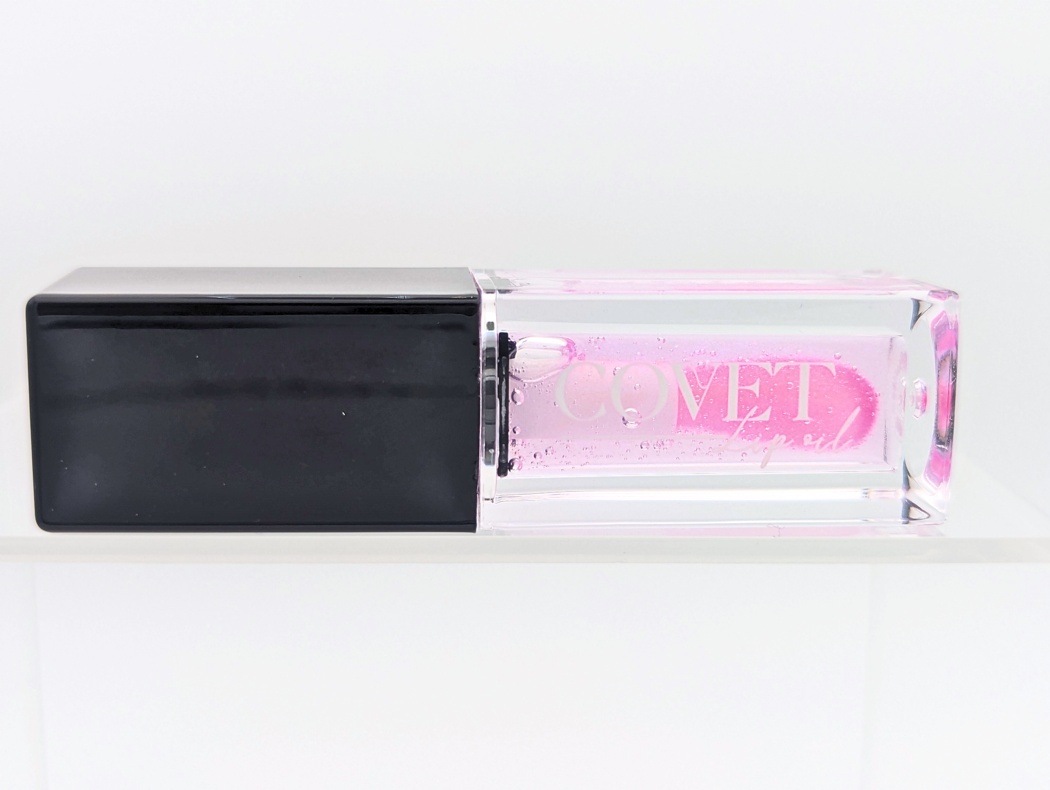 Covet Beauty’s Ocean of Stars lip gloss — a sheer violet gloss in a clear rectangular tube with black cap. Transforms into a soft cool pink based on skin pH and heat.