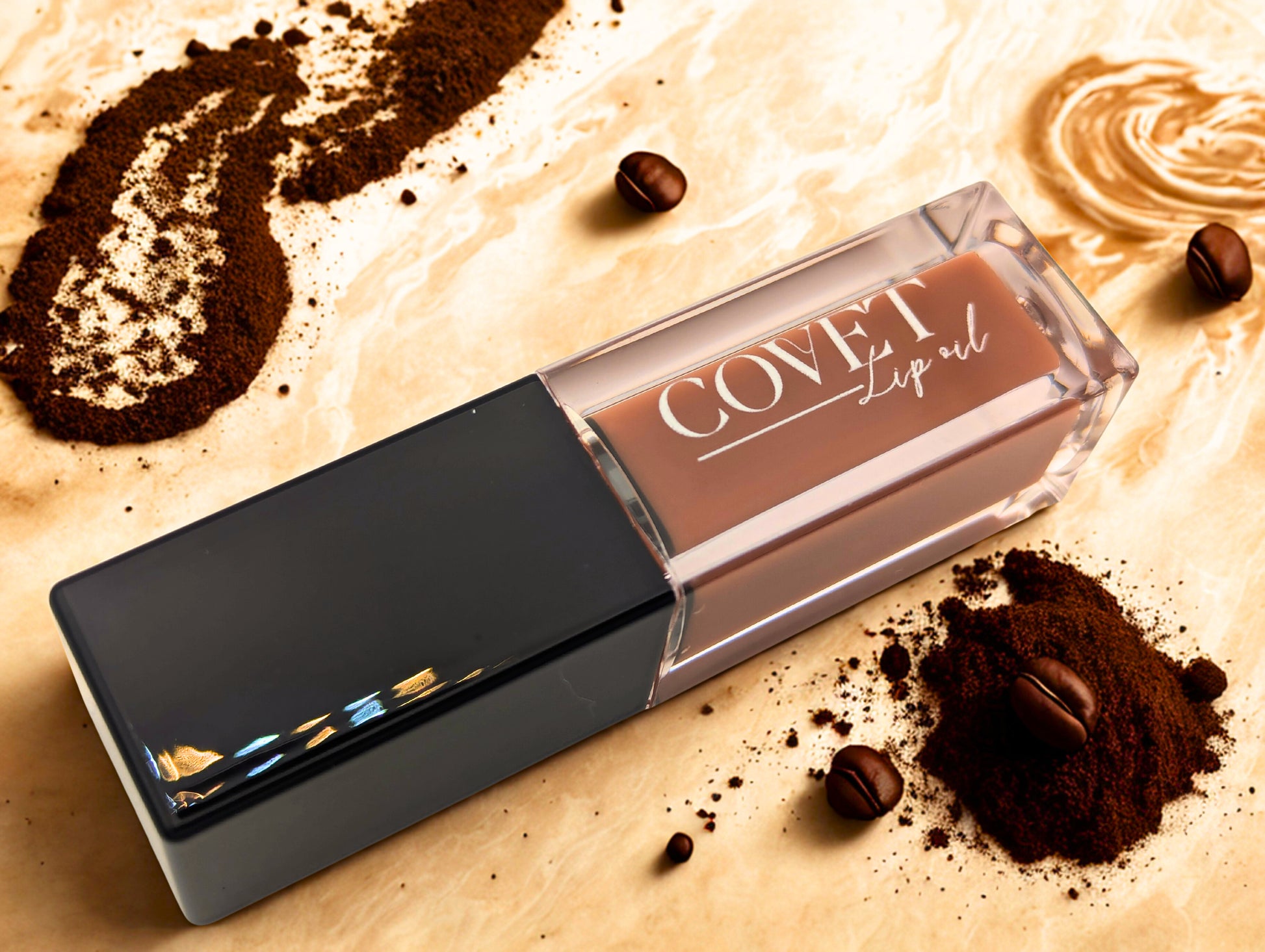 Covet Latte Cream lip gloss tube styled on a creamy coffee swirl background with espresso powder and coffee beans.