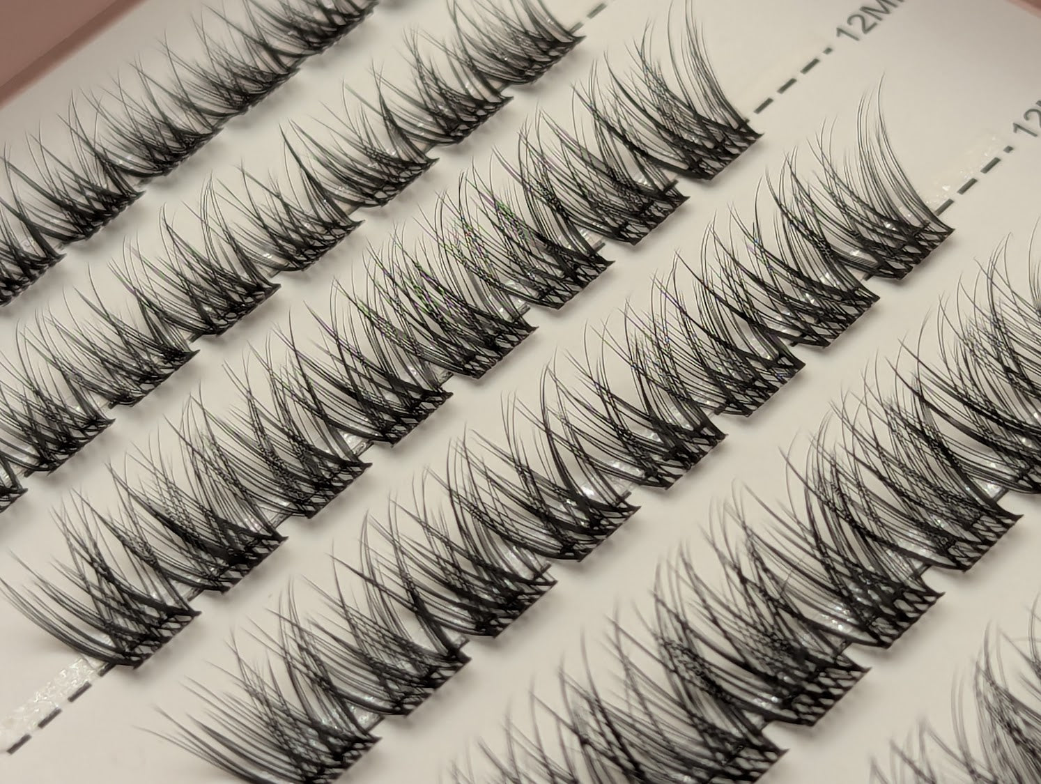 Covet Beauty Linger cluster lashes shown close-up in diagonal rows with soft curl and wispy lash fibers.
