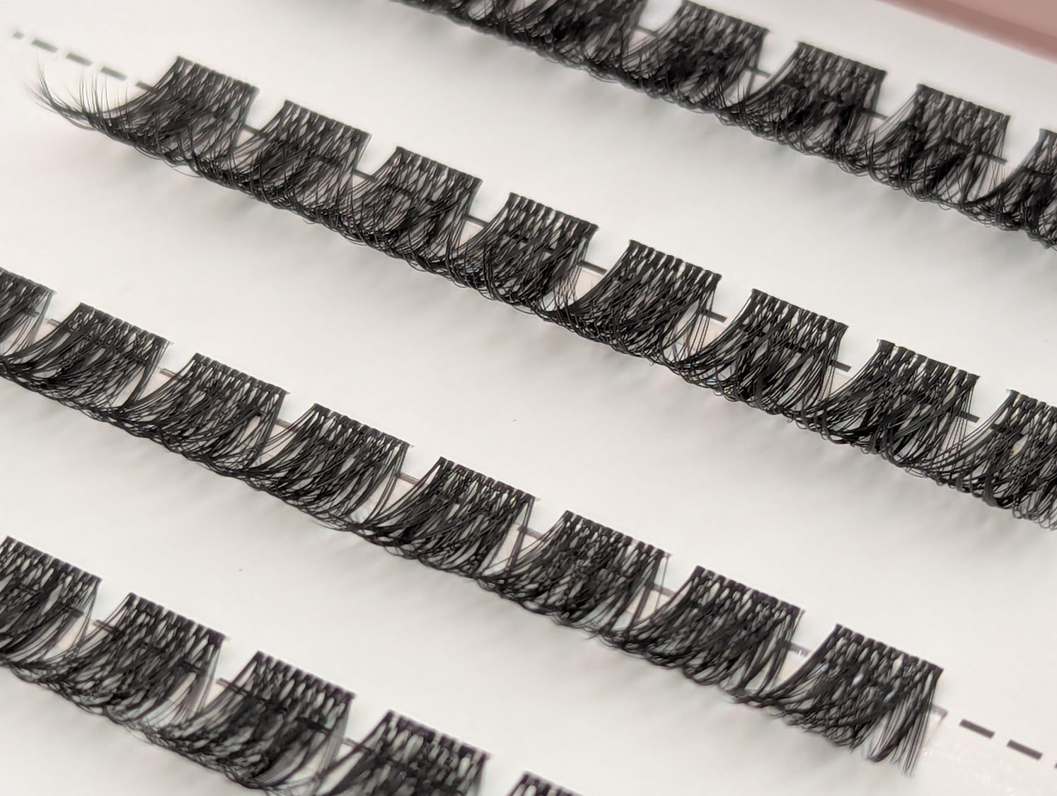 Covet Beauty Trance cluster lashes shown close-up in diagonal rows with soft curl and full, wispy lash fibers.