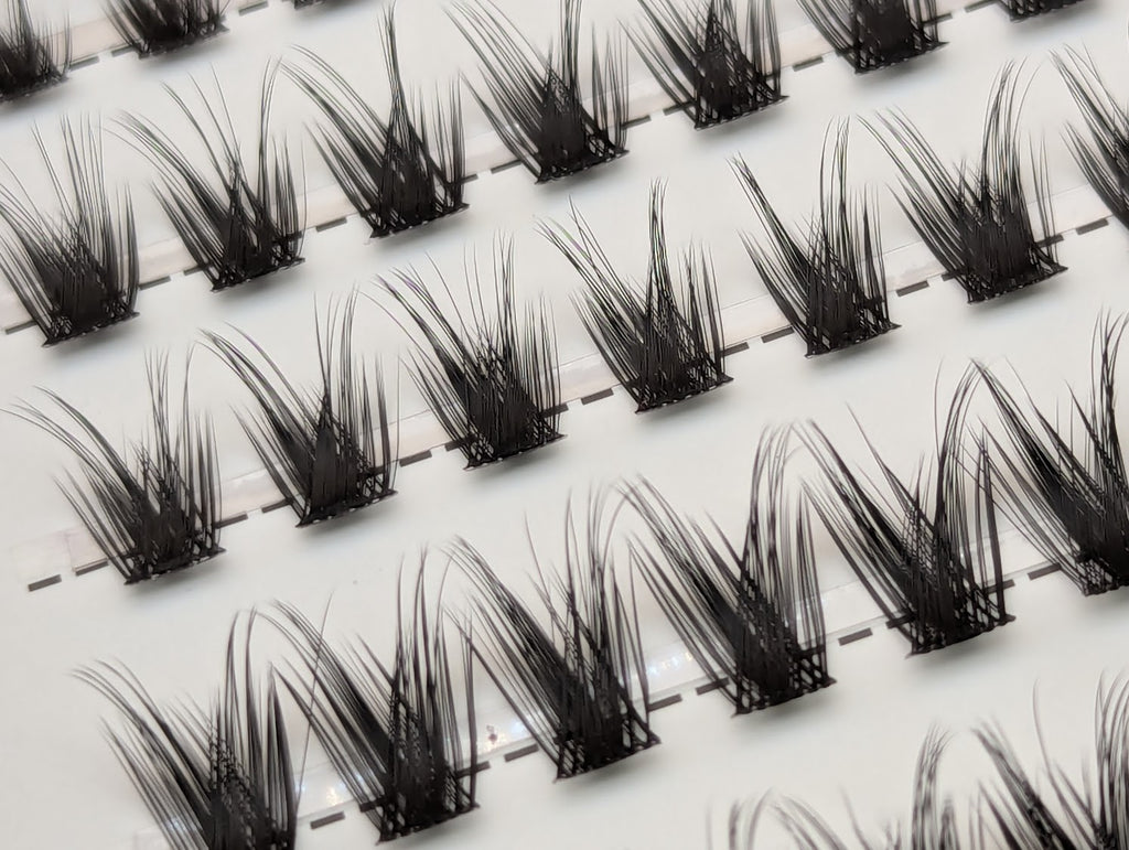 Close-up of Covet Beauty Control cluster lashes showing lifted, separated clusters with a defined lash pattern in the tray.