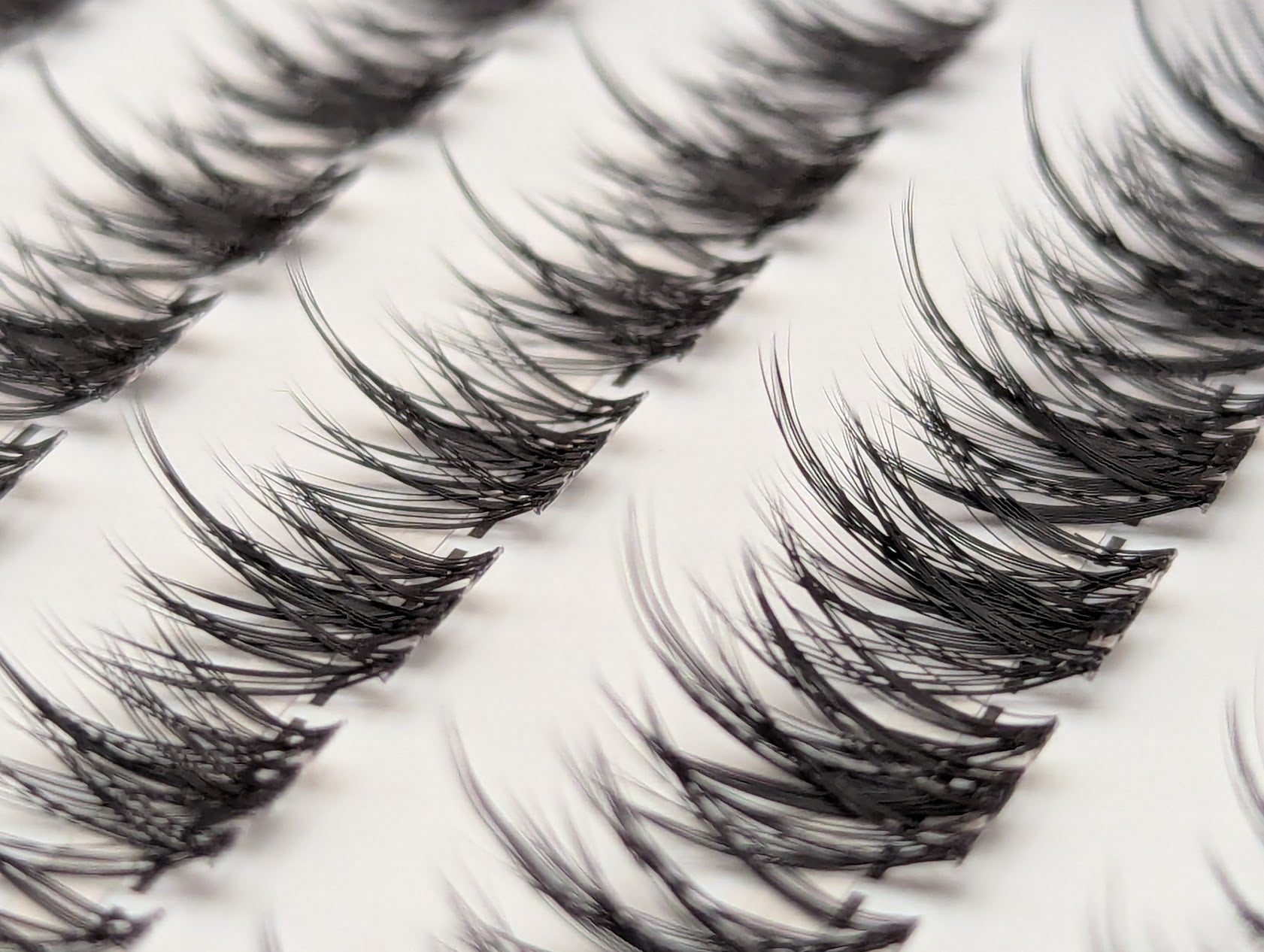 Covet Beauty Vision cluster lashes shown close-up with soft, airy fibers and a curved lash shape in the tray.