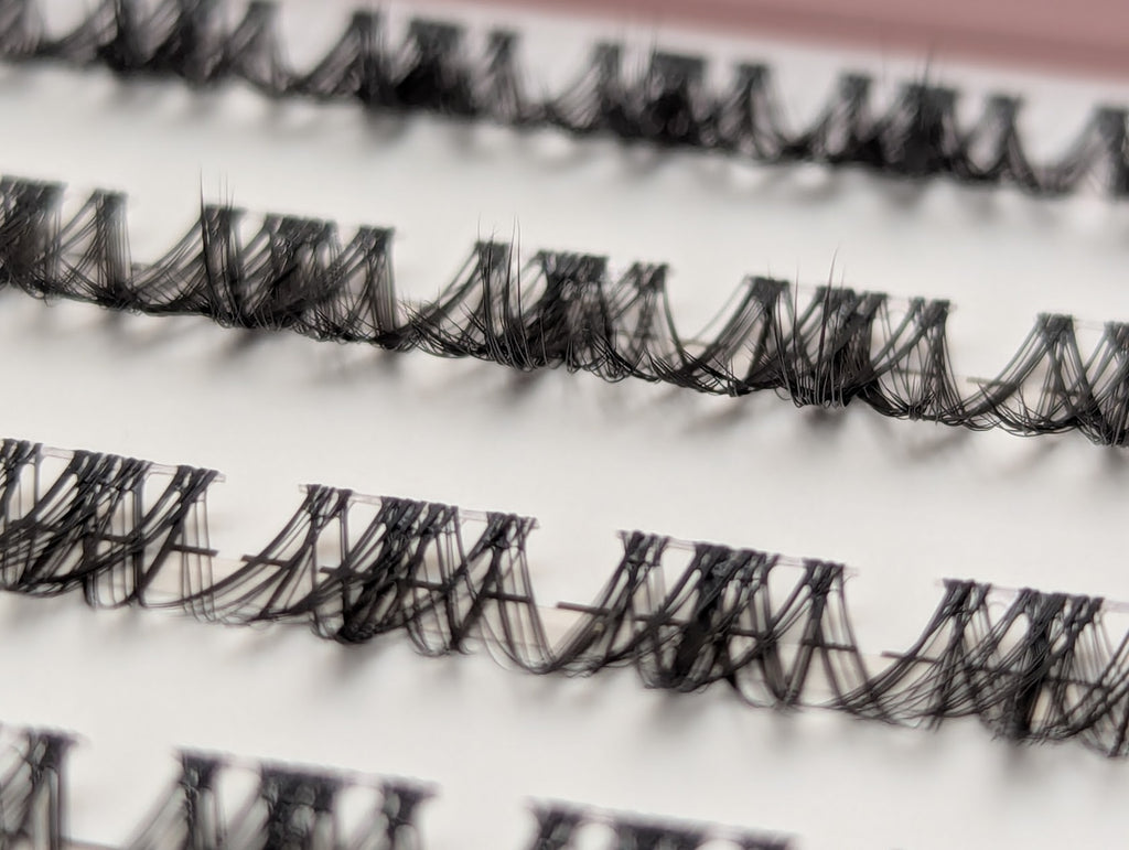 Close-up of Covet Beauty Vision cluster lashes showing the clear lash band and soft, airy fibers in the tray.