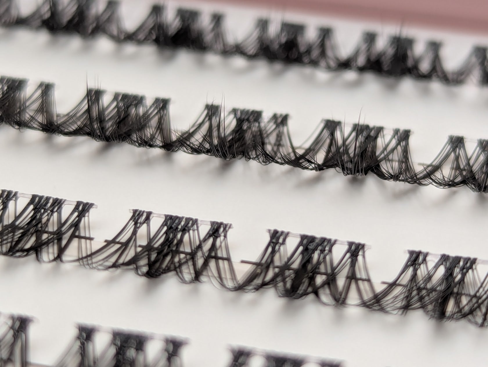 Close-up of Covet Beauty Vision cluster lashes showing the clear lash band and soft, airy fibers in the tray.