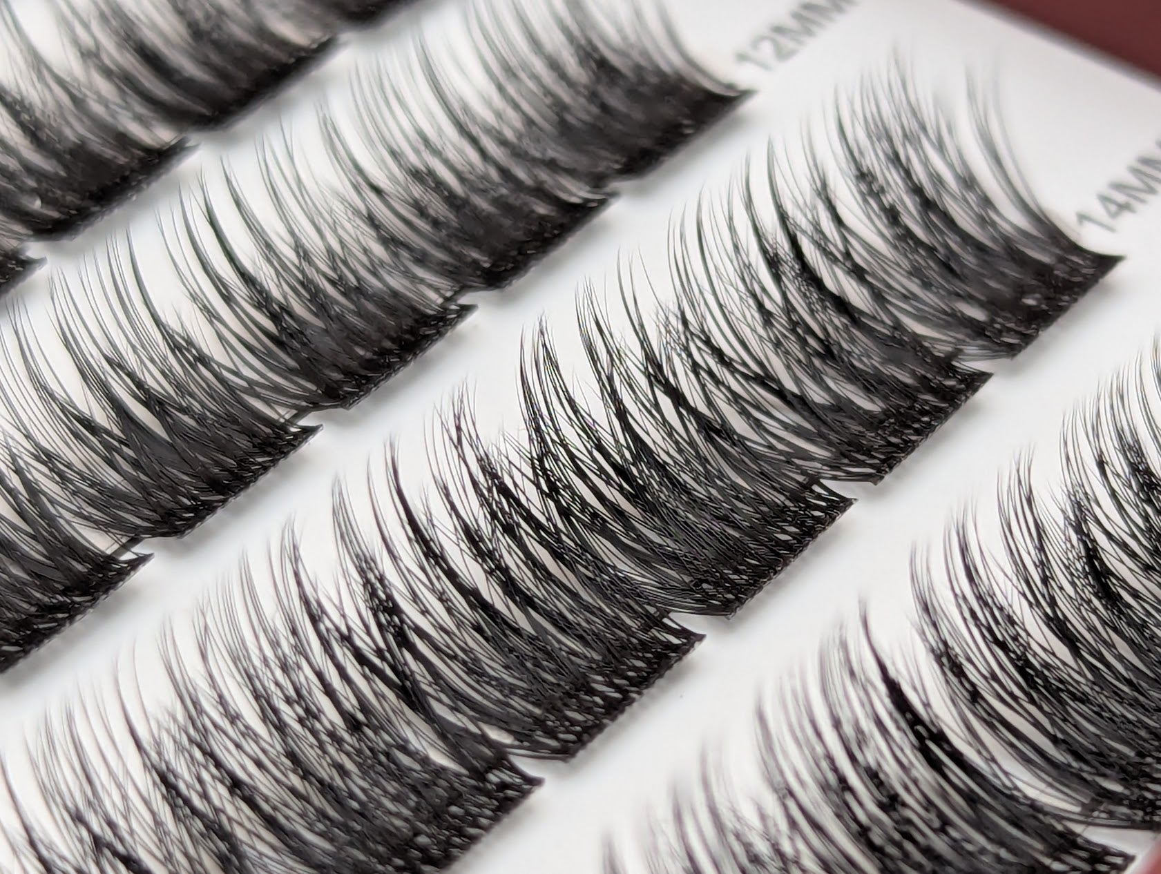 Covet Beauty Velvet cluster lashes shown close-up with dense, curled fibers and a defined lash pattern in the tray.