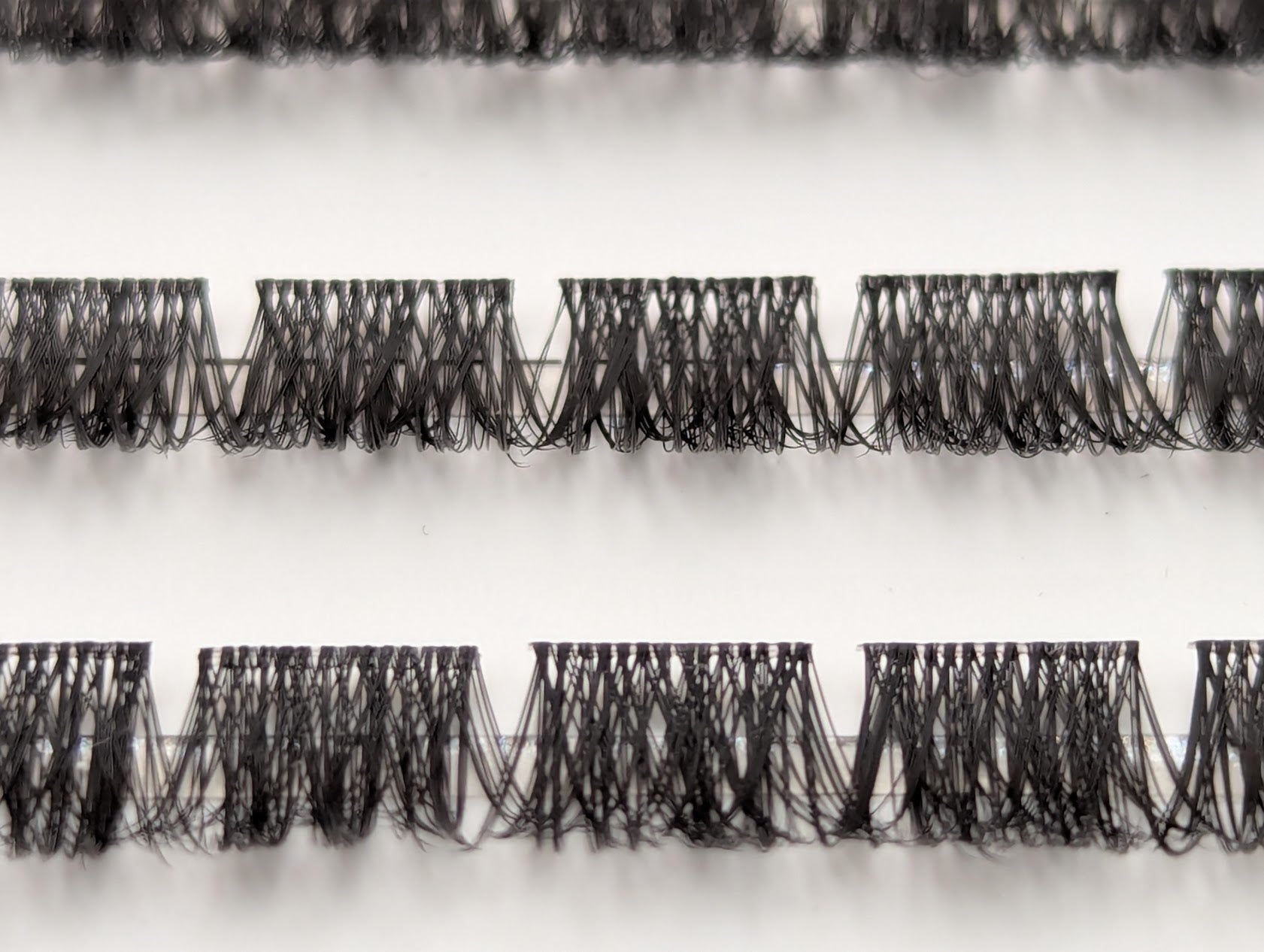 Close-up of Covet Beauty Velvet cluster lashes showing dense, compact lash segments and defined crisscross fibers in the tray.