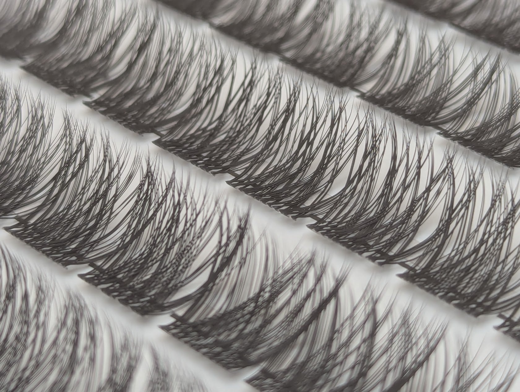 Covet Beauty Hush cluster lashes shown close-up with soft, wispy layered fibers in the tray.