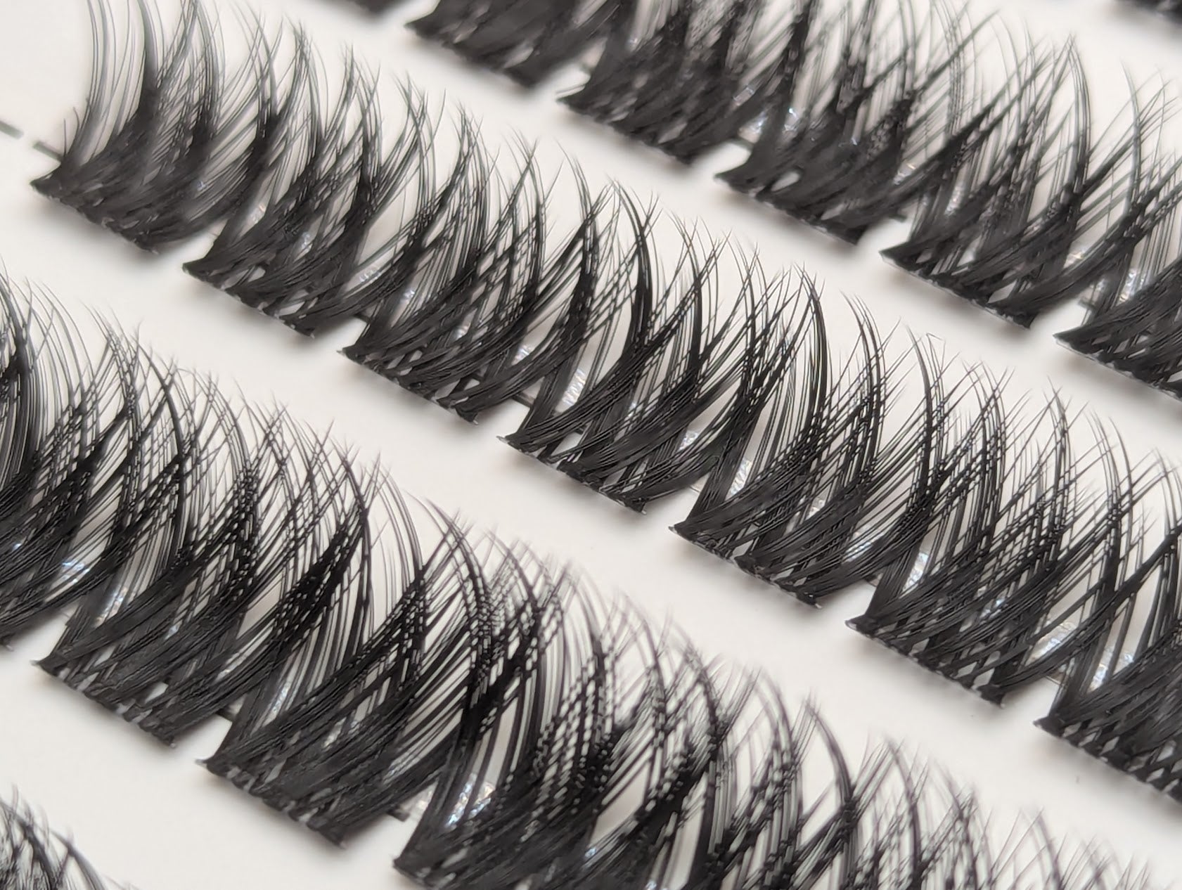 Close-up of Covet Beauty Obsession cluster lashes in the tray, showing rows of dense crisscross lash clusters.