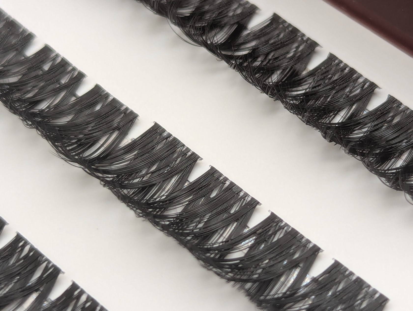 Covet Beauty Obsession cluster lashes in the tray, showing layered curl and dense crisscross fibers.