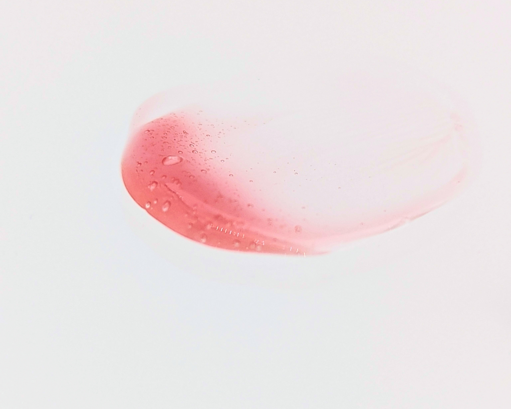 Swatch of Covet Beauty’s Rosewood lip gloss — a warm reddish-brown gloss with a creamy finish on a white background.