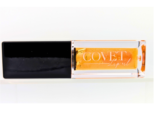 Covet Beauty’s Saturn lip gloss — a shimmering orange gloss in a clear rectangular tube with black cap. Transforms into a soft rose pink based on skin pH and heat.
