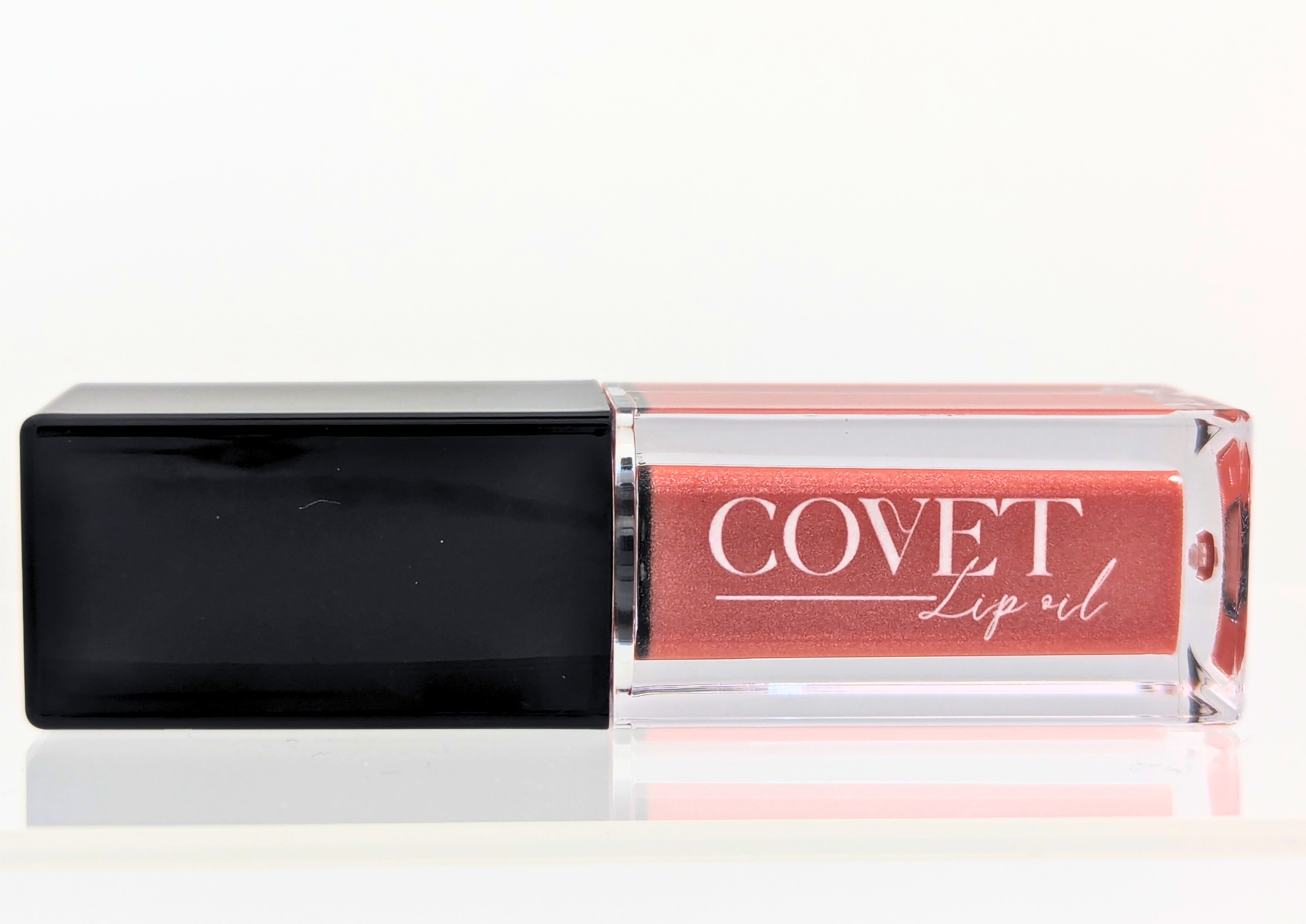 Covet Nude Pink lip gloss front-facing on a white surface, featuring a soft neutral pink tint in clear packaging.
