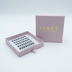 Covet Beauty Veil cluster lashes shown in an open pink tray beside matching logo packaging.