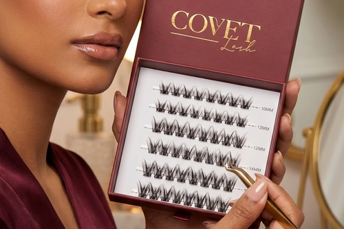 Covet Beauty Command cluster lashes shown in an open burgundy tray near a model’s face while tweezers point to a lash row.