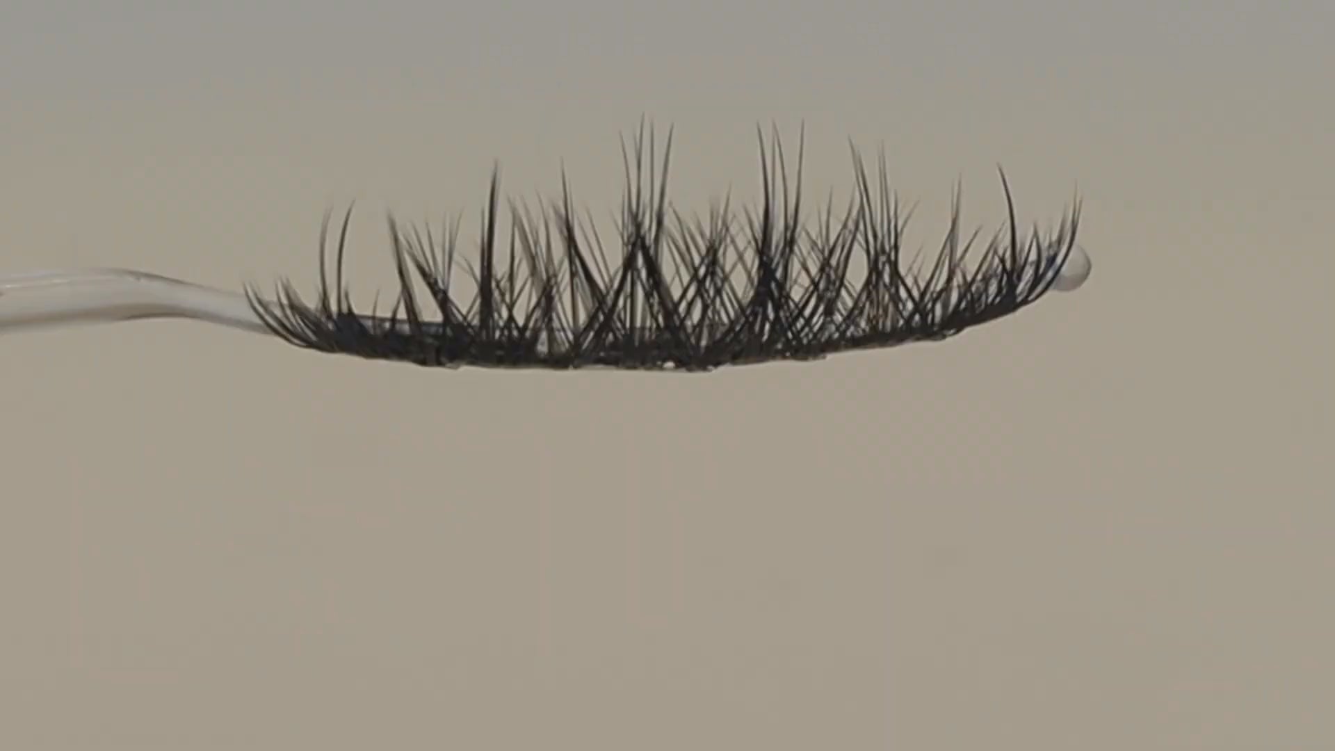 Covet Beauty Vision cluster lashes shown on a display wand, moving up and down to highlight the soft curl and airy crisscross pattern.